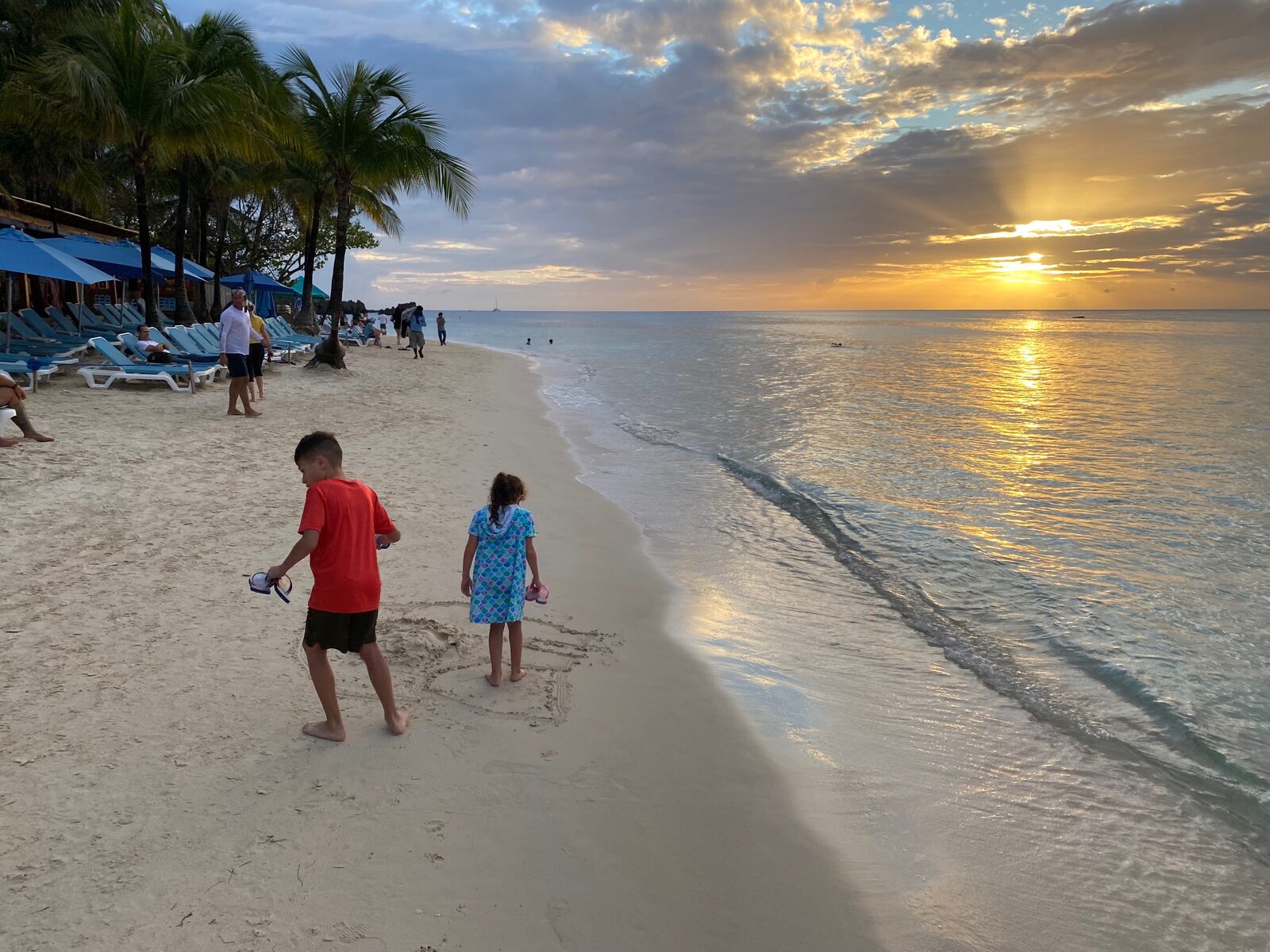 Sunset over West Bay Beach with children playing in the sand